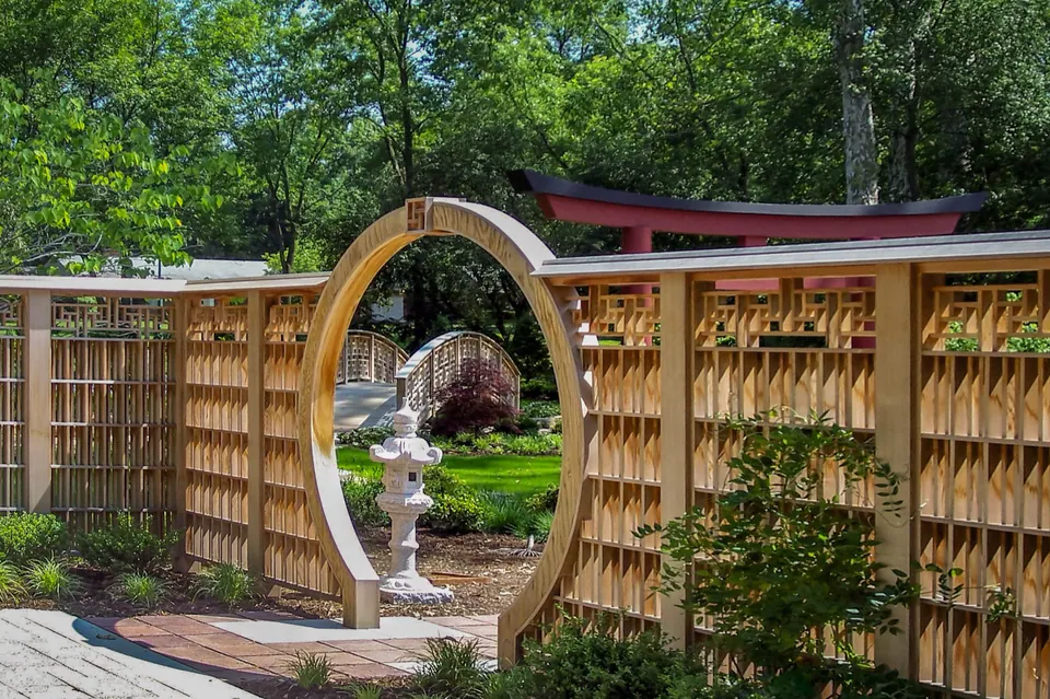 Circular wood moon gate set into a decorative garden fence